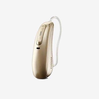 A beige, behind-the-ear hearing aid device with a clear, thin tube and the brand name Phonak printed on its side, displayed on a plain white background.